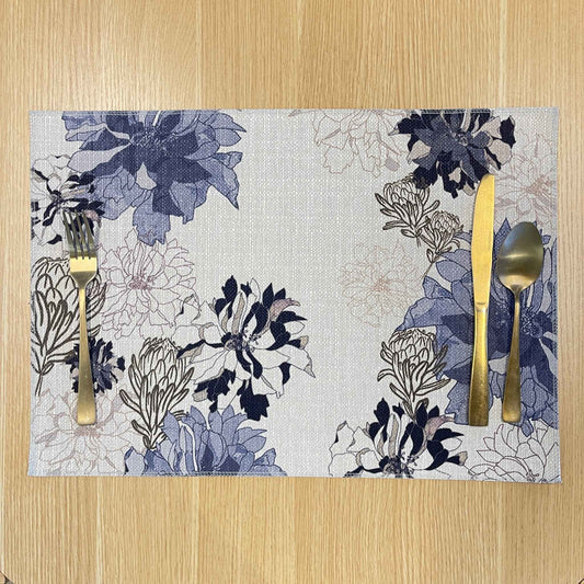 Rectangular Antique Floral Blue placemat with navy and blue flowers with fine floral outlines on a pale background, on a wooden tabletop with gold cutlery.