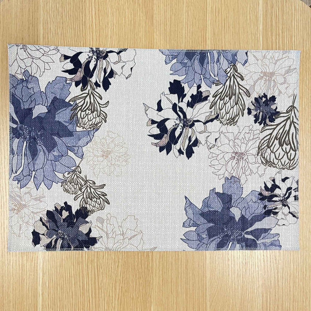 Rectangular Antique Floral Blue placemat with navy and blue flowers with fine floral outlines on a pale background, on a wooden tabletop.