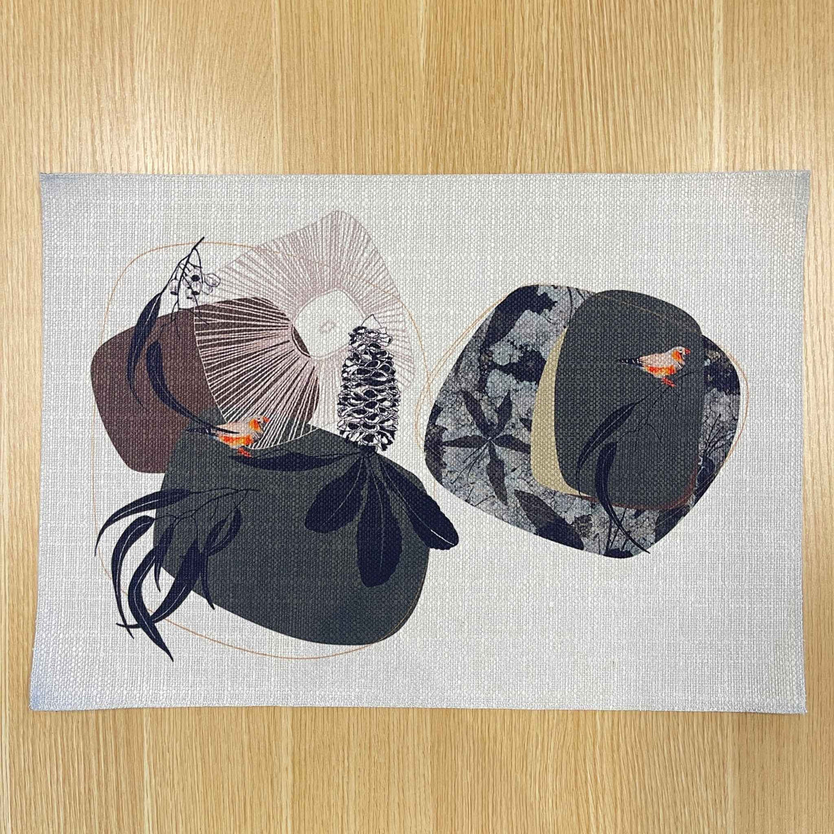 Rectangular Geo Finch placemat with orange-accented finches among black organic shapes and fine geometric lines, on a wooden tabletop.