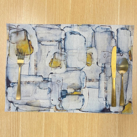Rectangular Mid Century placemat with abstract grey and blue shapes with ochre accents, on a wooden tabletop.