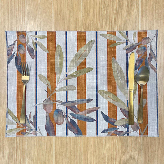 Rectangular Olive and Sol placemat with olive branches over terracotta and navy stripes, on a wooden tabletop with gold cutlery.