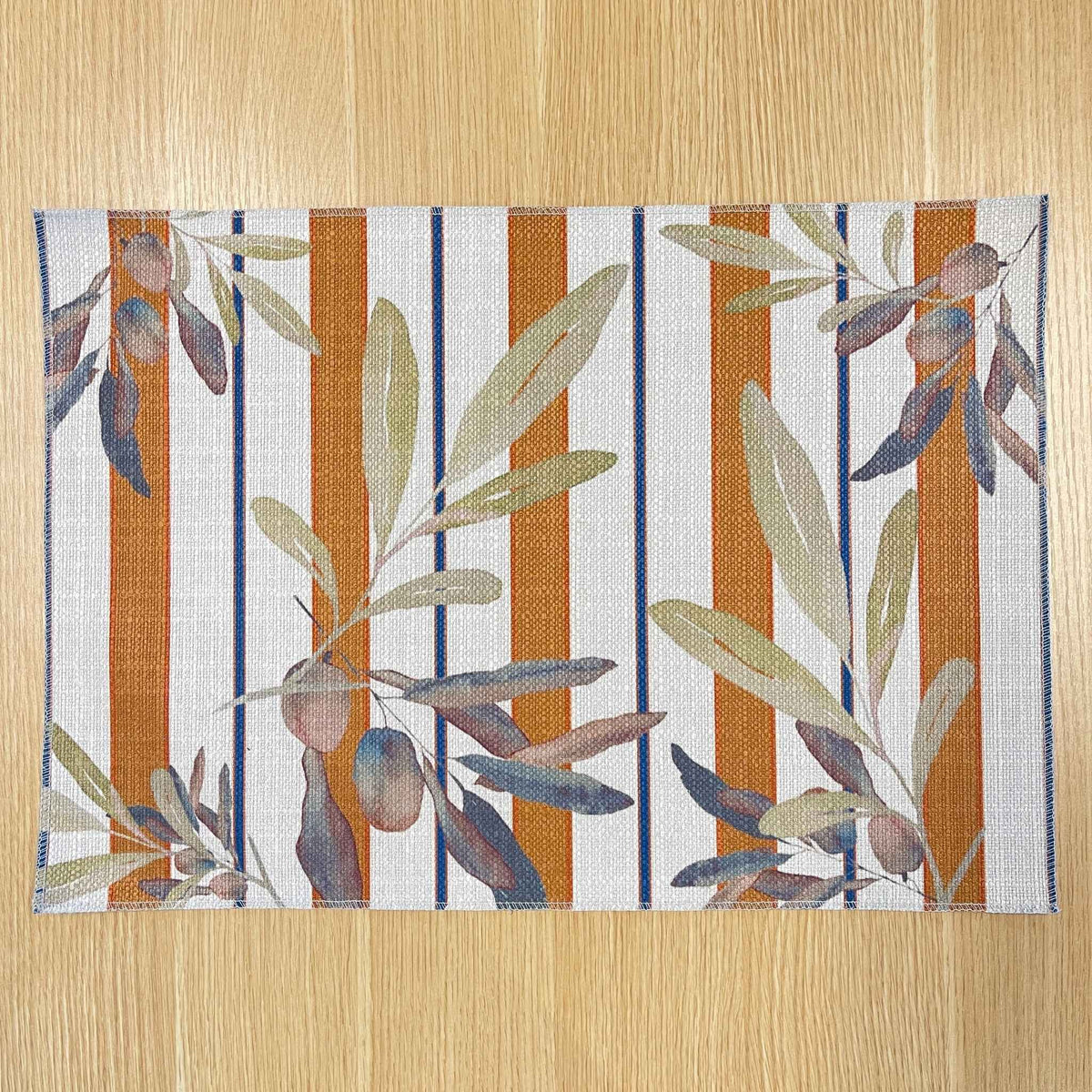 Rectangular Olive and Sol placemat with olive branches over terracotta and navy stripes, on a wooden tabletop.