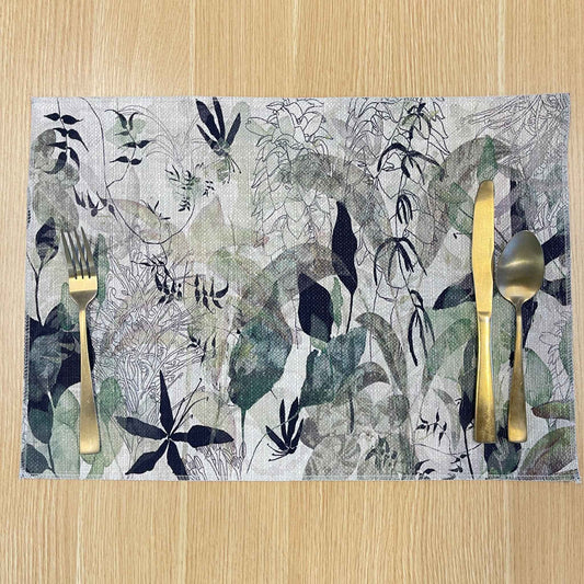 Rectangular Springtime placemat with layered grey and green foliage with fine black floral outlines, on a wooden tabletop with gold cutlery.