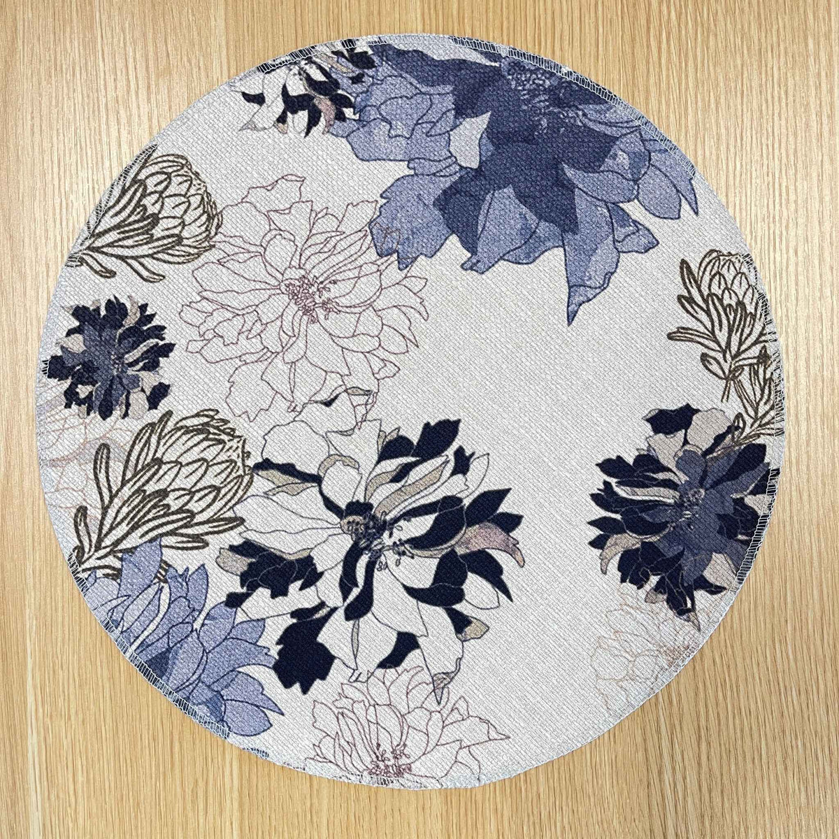 Round Antique Floral Blue placemat with navy and blue flowers with fine floral outlines on a pale background, on a wooden tabletop.
