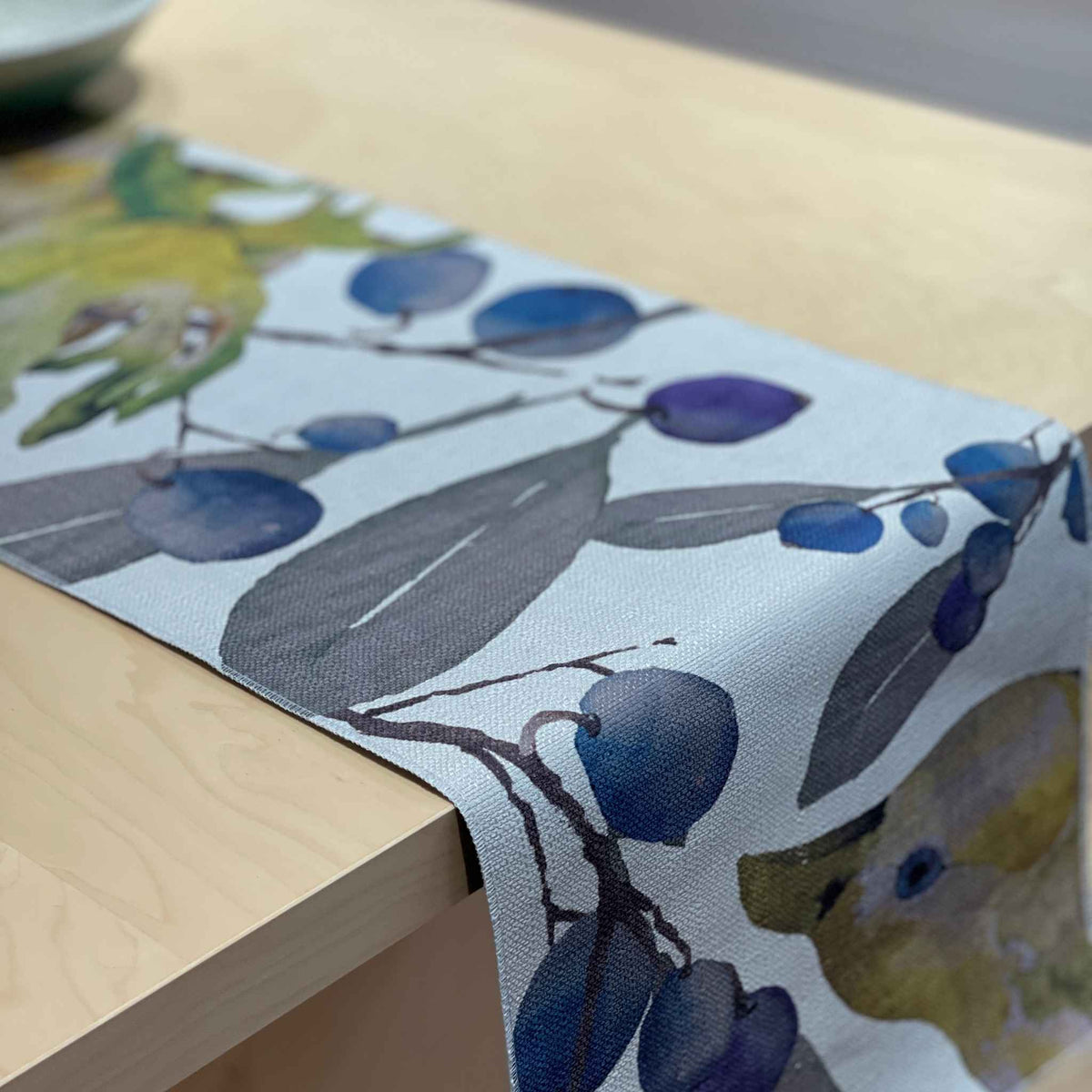 Bower table runner with a green bowerbird among blue-purple berries and green foliage